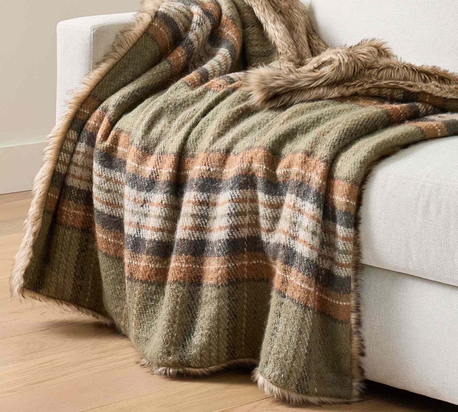 Plaid throw blanket with fur trim draped over a couch arm