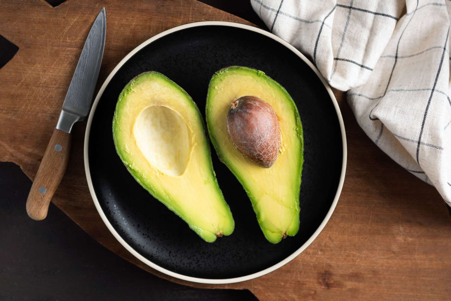 Avocado cut in halves on plate, top view. Tropical fruit rich in omega 3 fatty acids. Healthy food