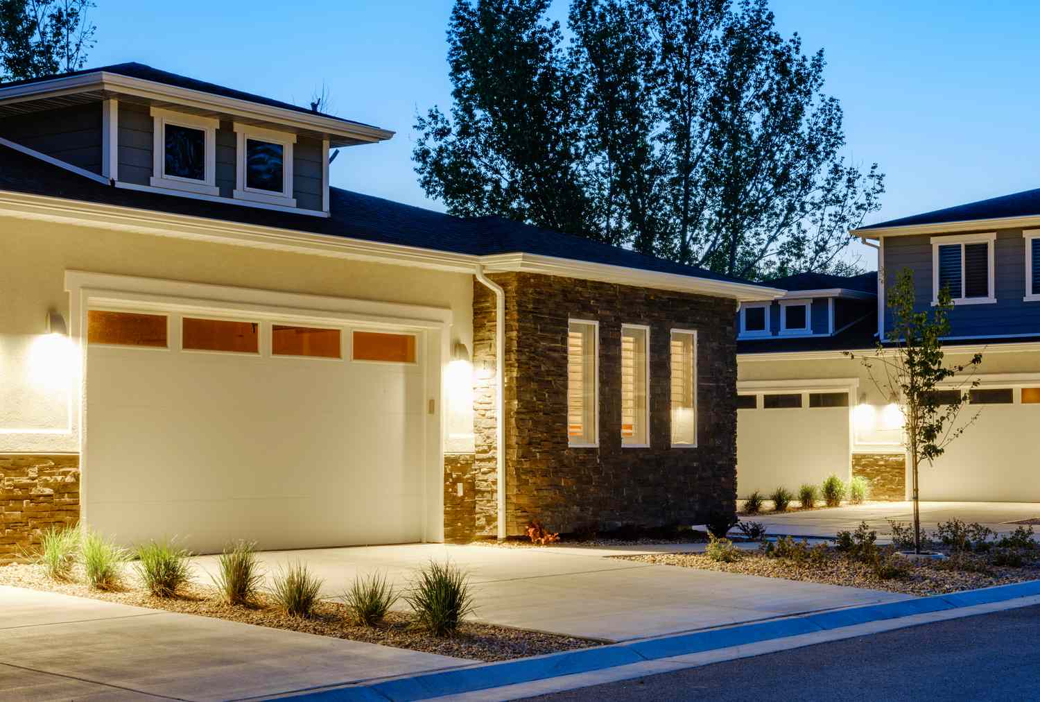 Suburban homes with garages lit at dusk