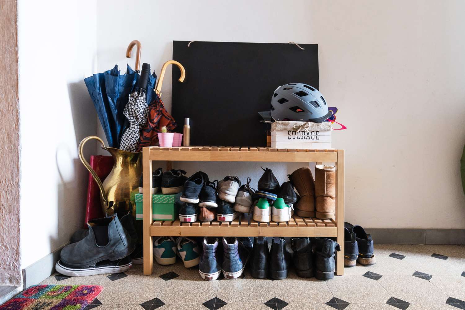 Shoe rack with various footwear helmet and umbrellas nearby