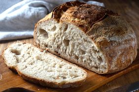 Loaf of rustic bread with a slice cut on a wooden board