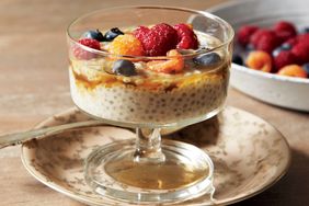 A glass serving bowl of chia pudding topped with assorted berries on a decorative plate