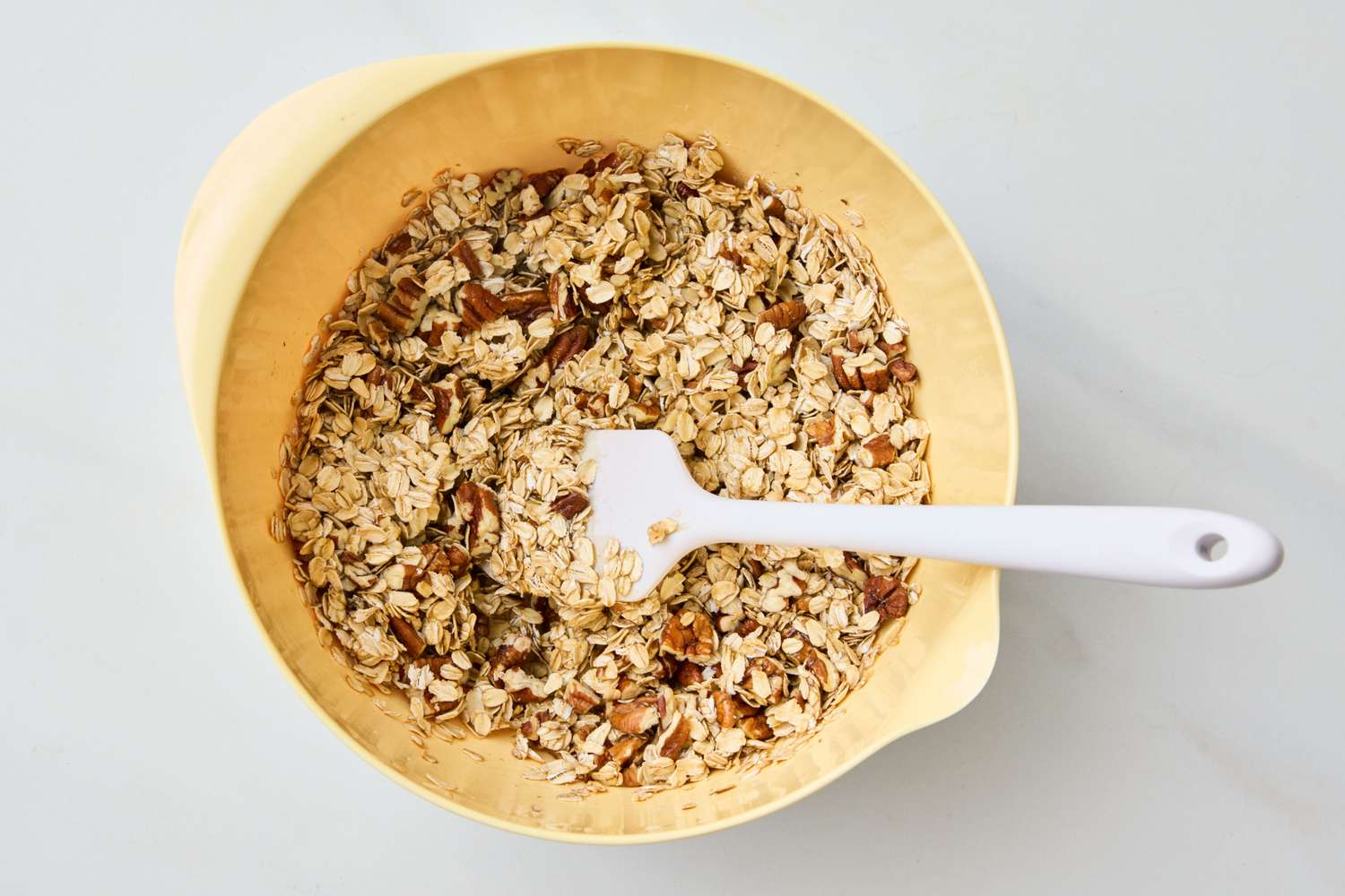 A bowl of granola mix with a spatula