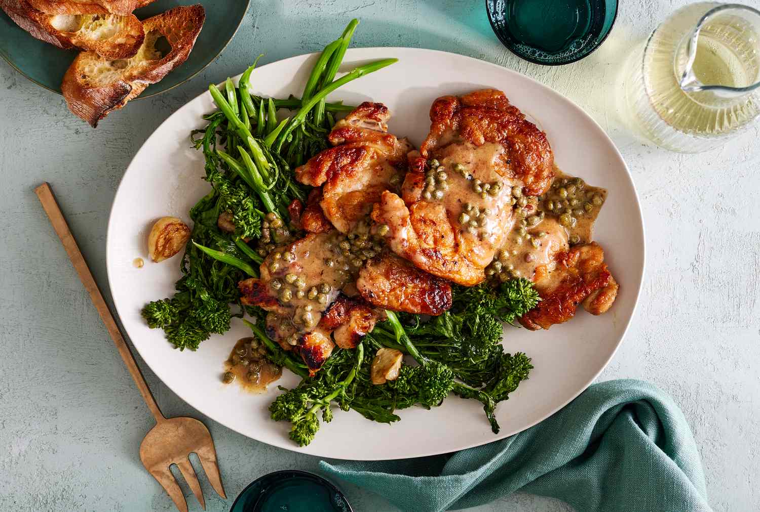 Plate of cooked chicken thighs with sauce and broccolini