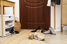Entryway with scattered shoes a shoe rack and a basket near a door