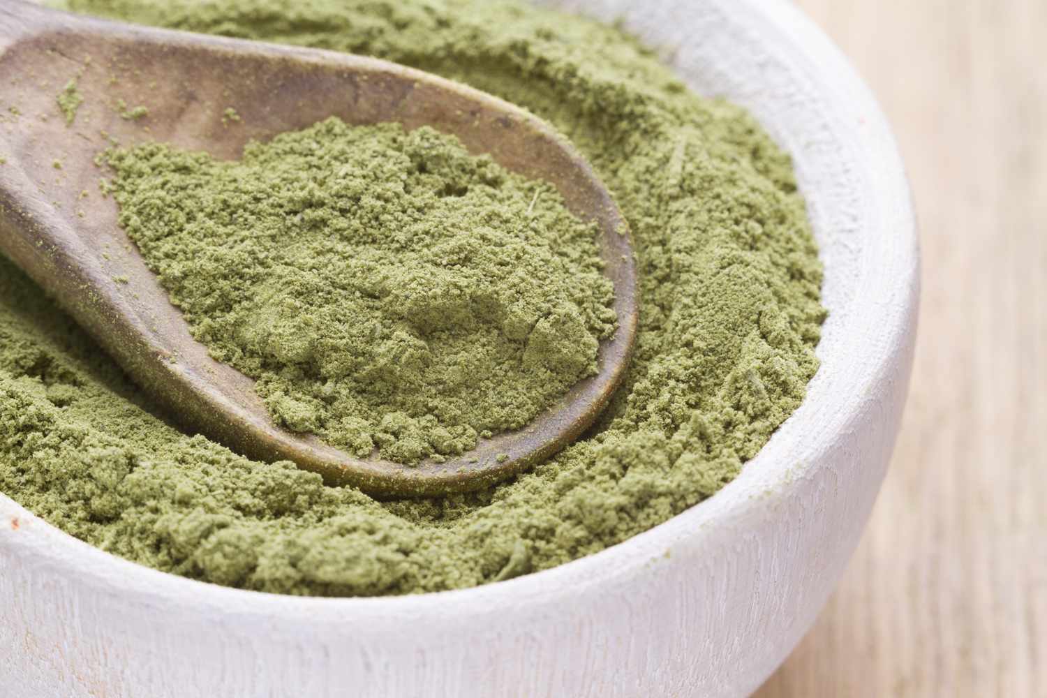 Wooden spoon in a bowl of powdered green material