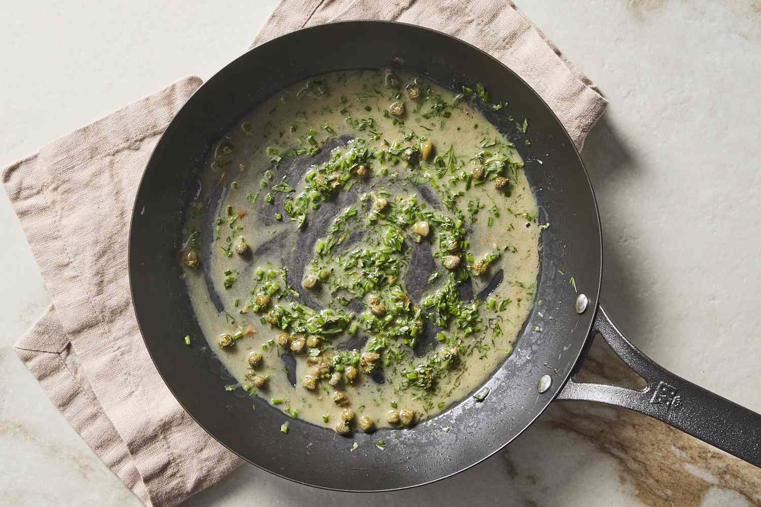 Capers, herbs and butter in a pan
