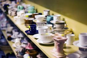 A variety of ceramic cups and containers arranged on shelves in a store or display area