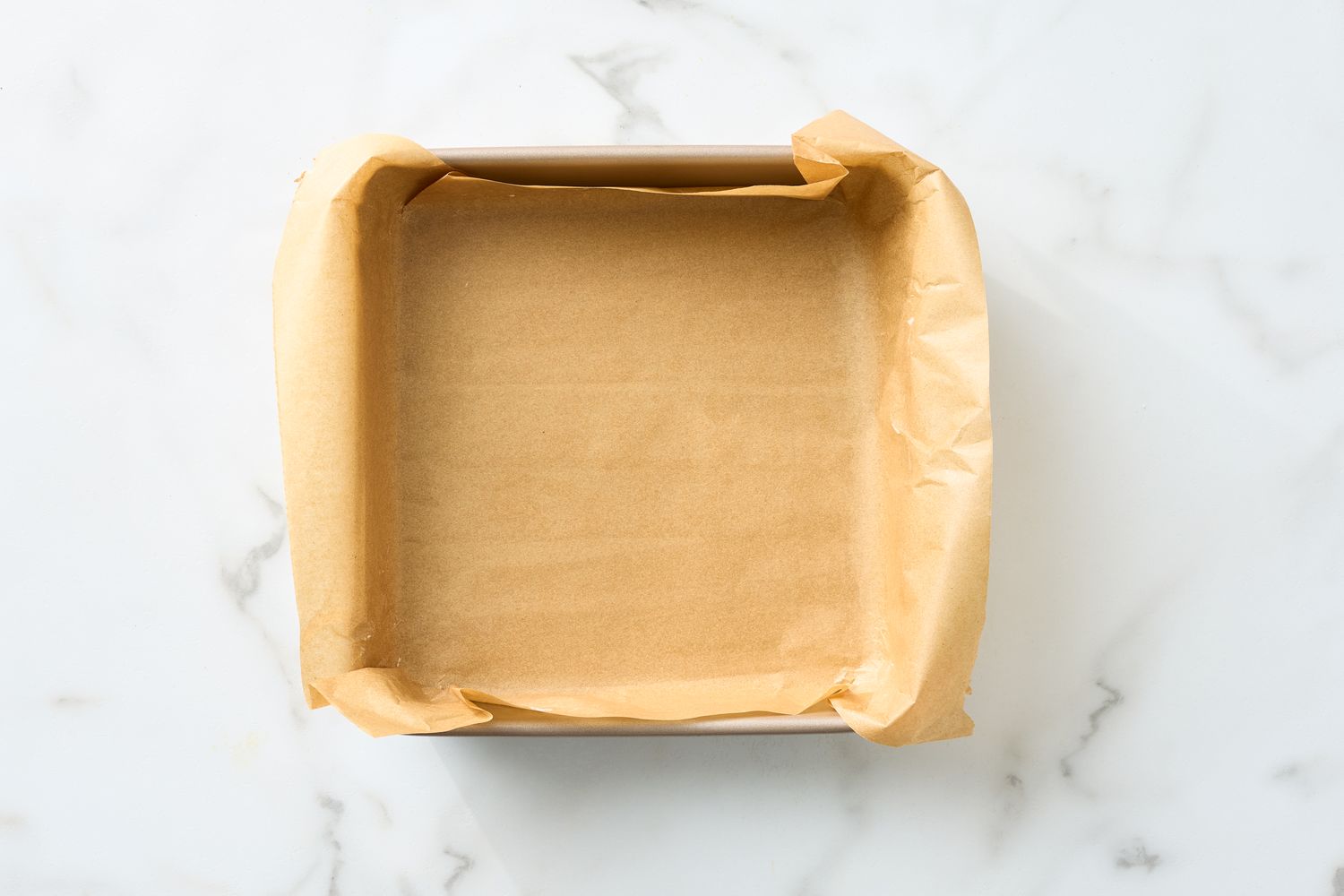 Square baking pan lined with parchment paper ready for baking