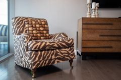 An upholstered armchair with a zebra print next to a wooden dresser and candles
