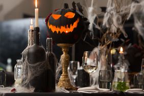 Table set for Halloween dinner. Served holiday table with candles and pumpkin. black tablecloth