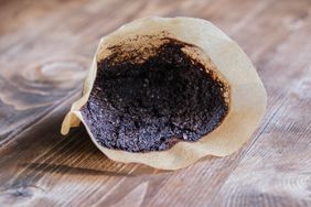 Used coffee grounds in a paper filter on a wooden surface