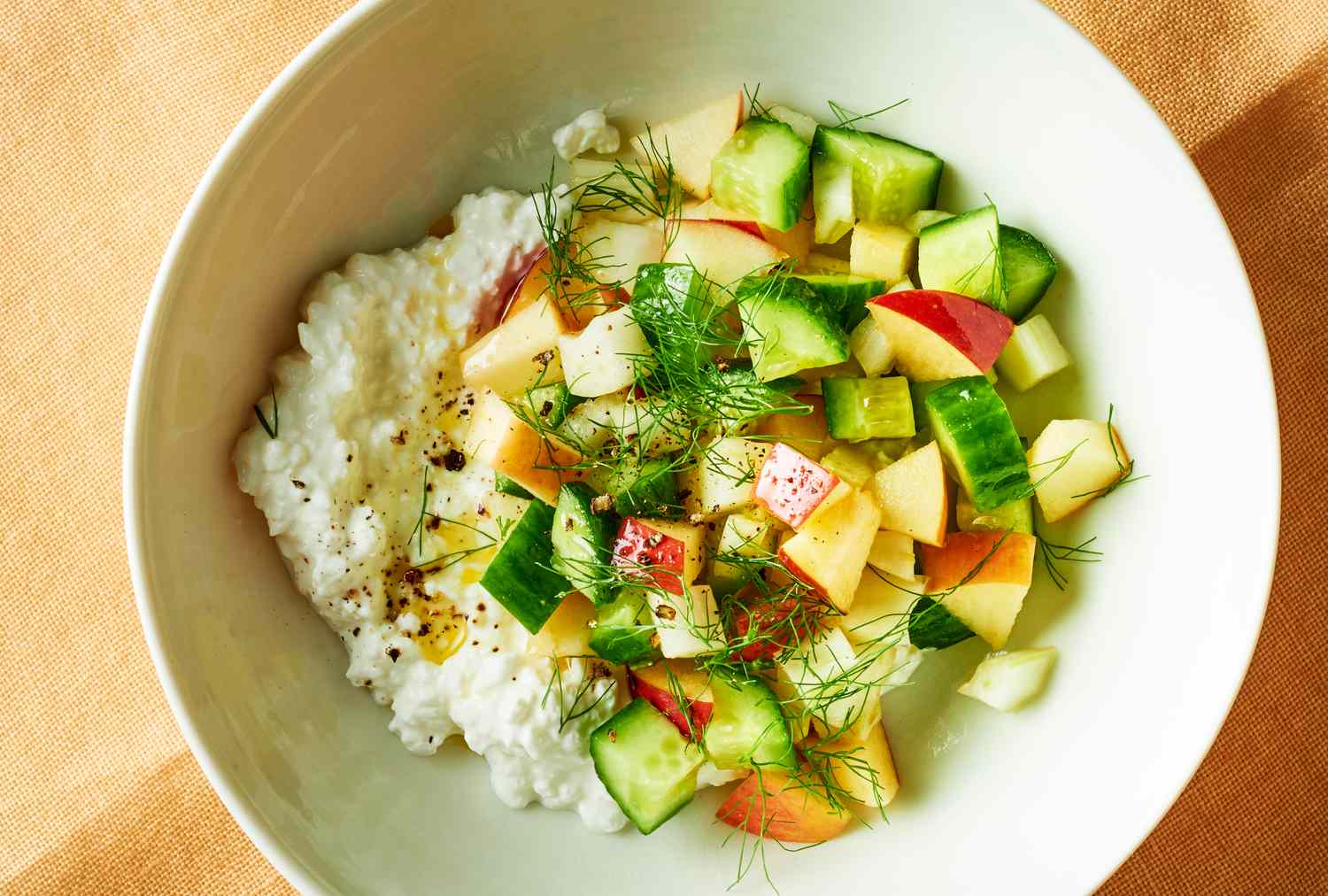 Bowl with cottage cheese diced cucumbers apples and herbs