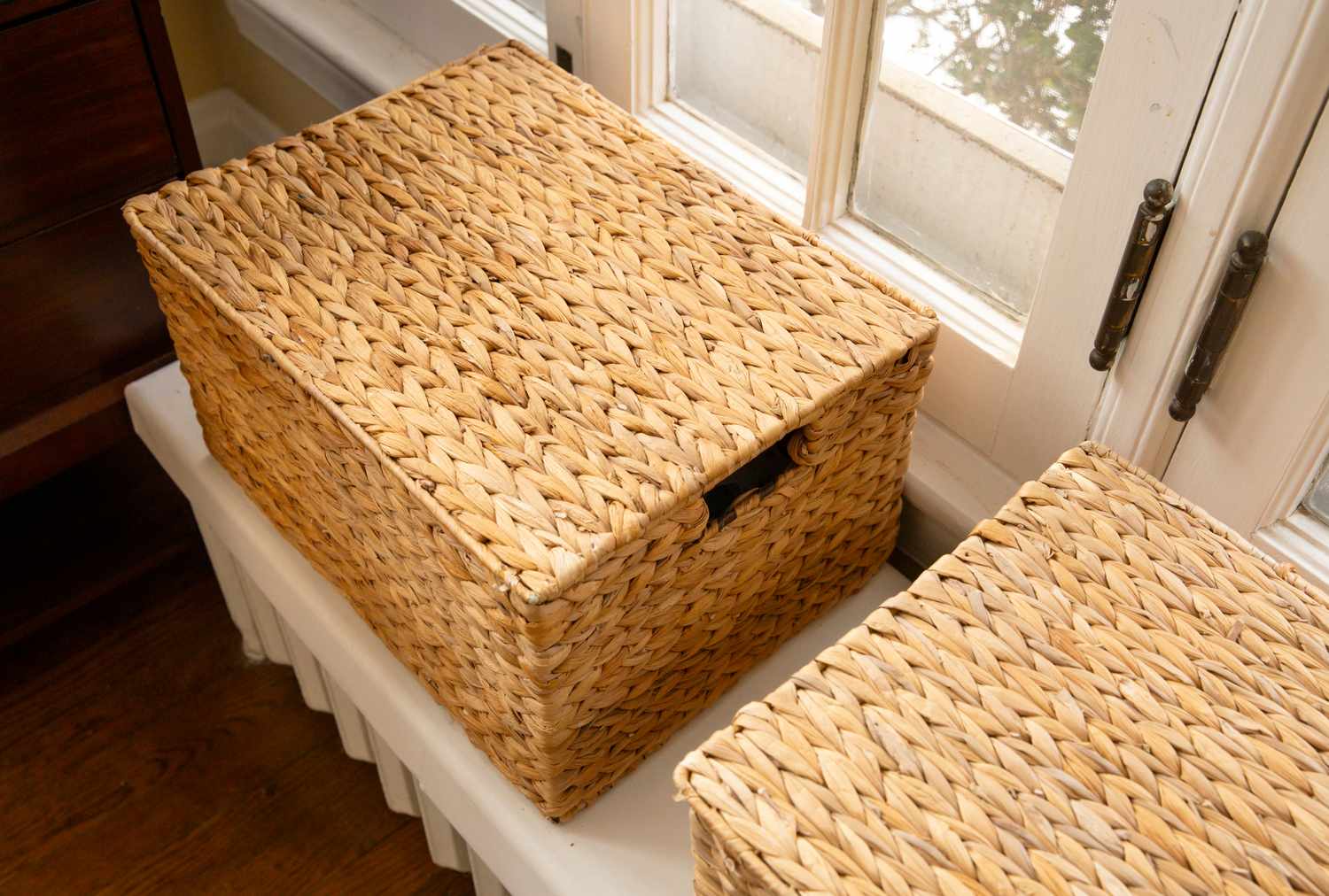 Woven storage baskets on a window sill one open with contents not visible