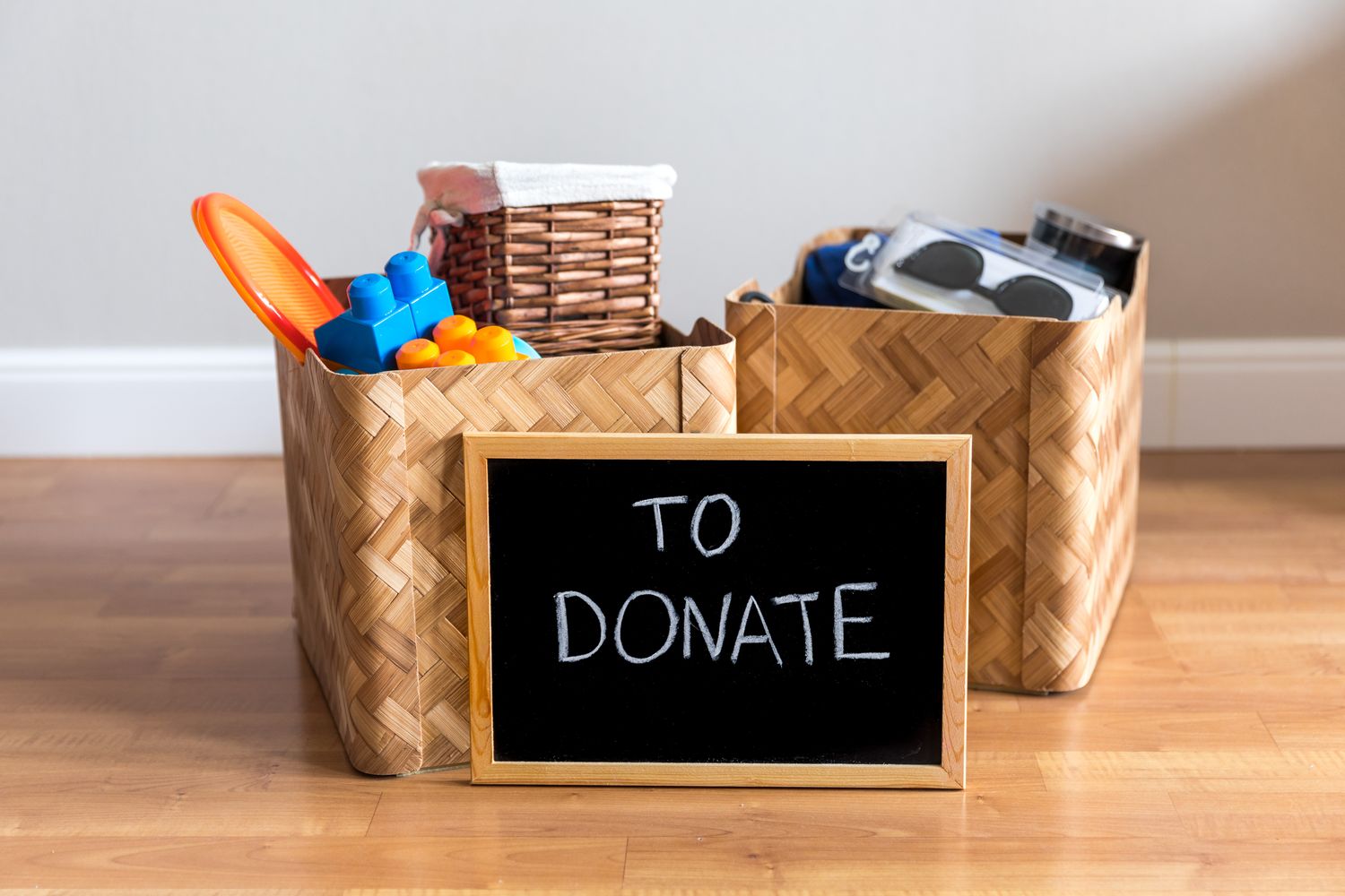 Baskets containing toys and household items with a small chalkboard sign reading To Donate in front