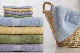 Stack of folded towels next to a basket with another towel draped over it