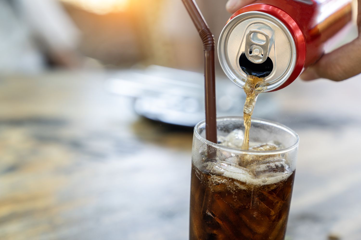 Can of soda being poured into glass