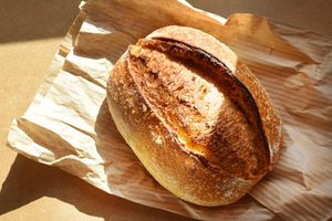 A loaf of sourdough bread on a crumpled paper bag