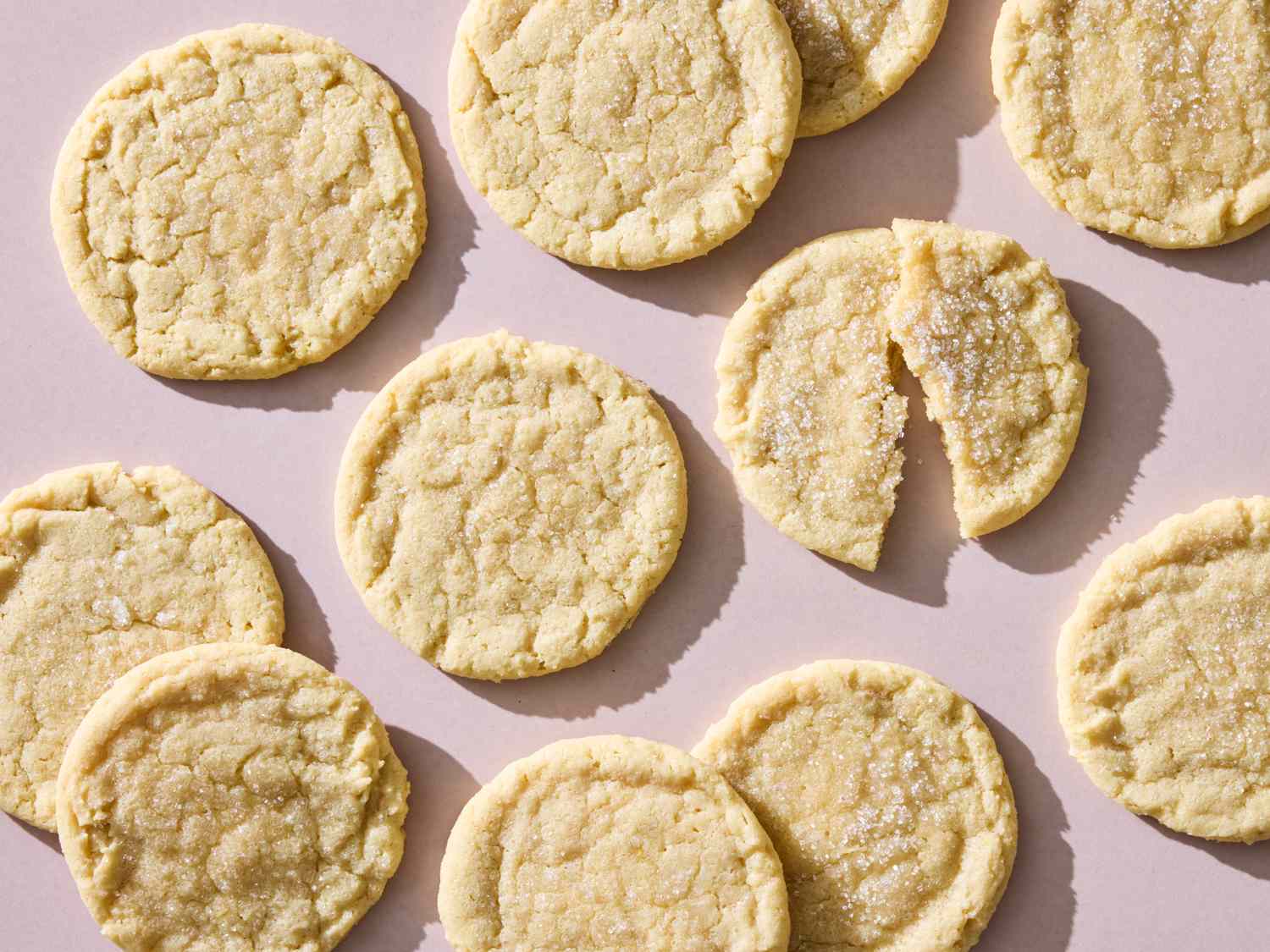 Several sugar cookies arranged on a surface one partially broken