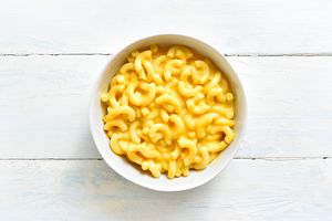 A bowl of macaroni and cheese on a wooden surface