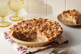 apple pie with piece removed, forks and drinks in background