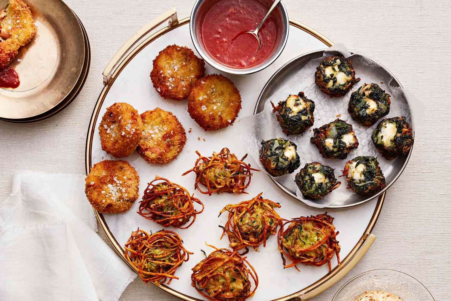 A plate featuring various appetizer dishes including fritters stuffed mushrooms and vegetablebased bites with dipping sauce