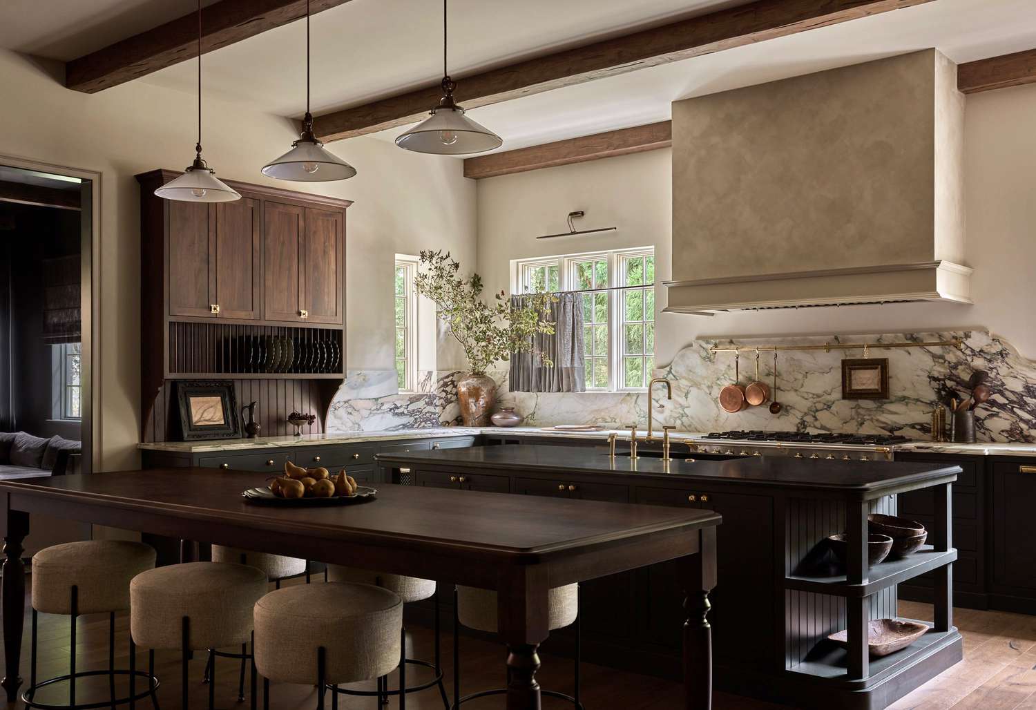 Modern kitchen with marble backsplash, wooden cabinets, and a breakfast table with stools