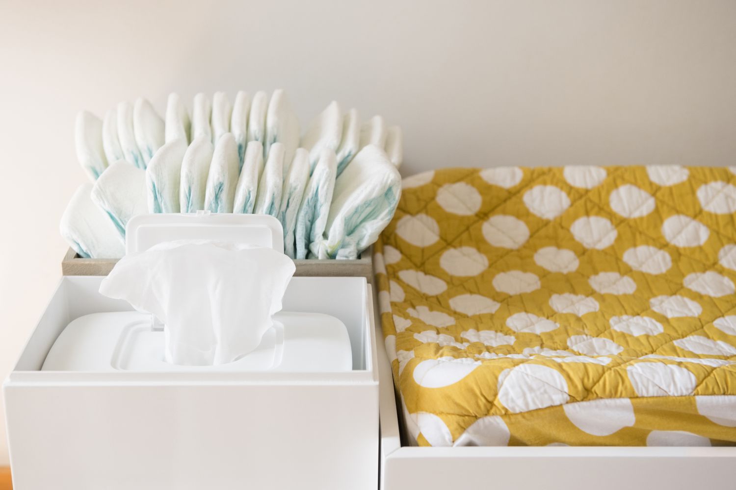 A baby changing station with diapers wipes and a patterned mat