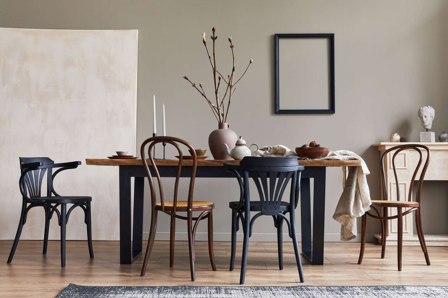 rustic interior of dining room with walnut wooden table, retro chairs, decoration, fireplace, dried flower, candlestick mock up picture frame and carpet