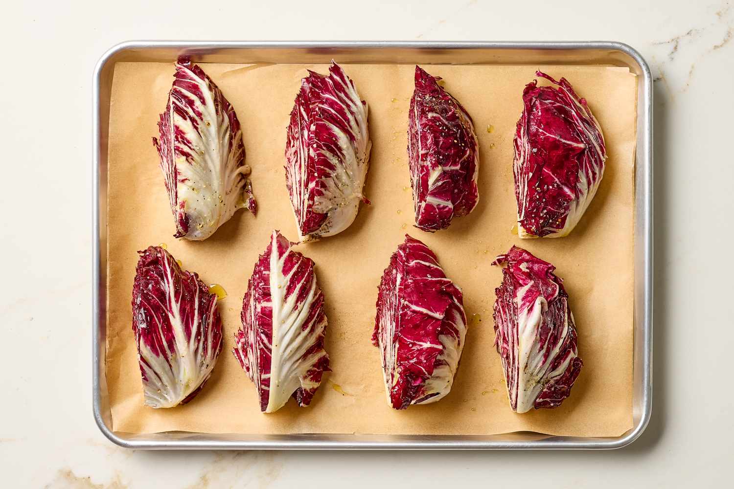 Eight roasted radicchio halves laid out on a parchmentlined baking sheet