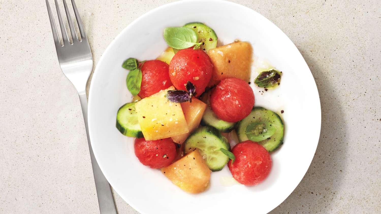 watermelon, cantaloupe, and cucumber salad on a white plate