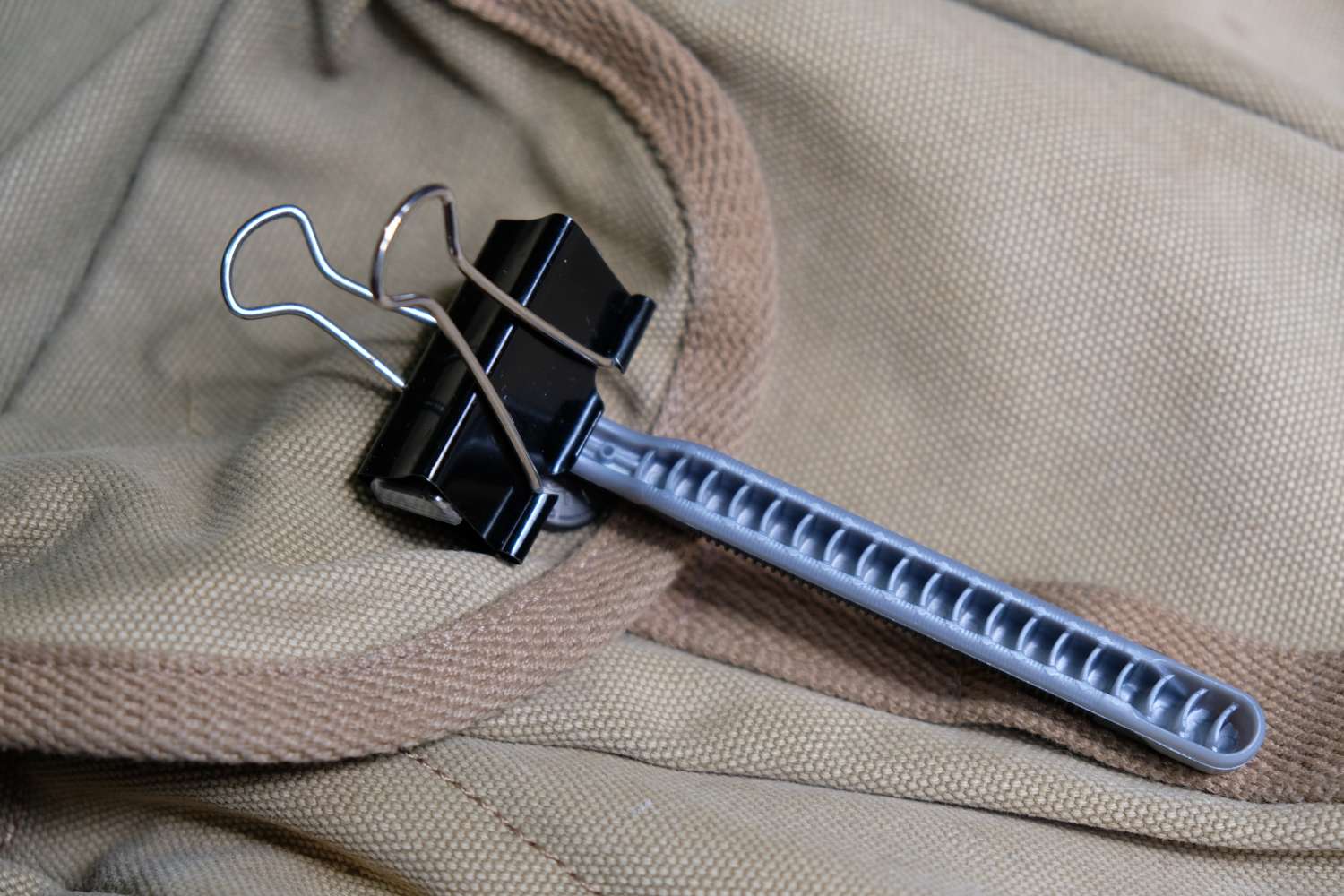 A binder clip attached to a zipper pull on a fabric bag