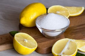 Lemons and a small bowl of granulated sugar on a wooden board
