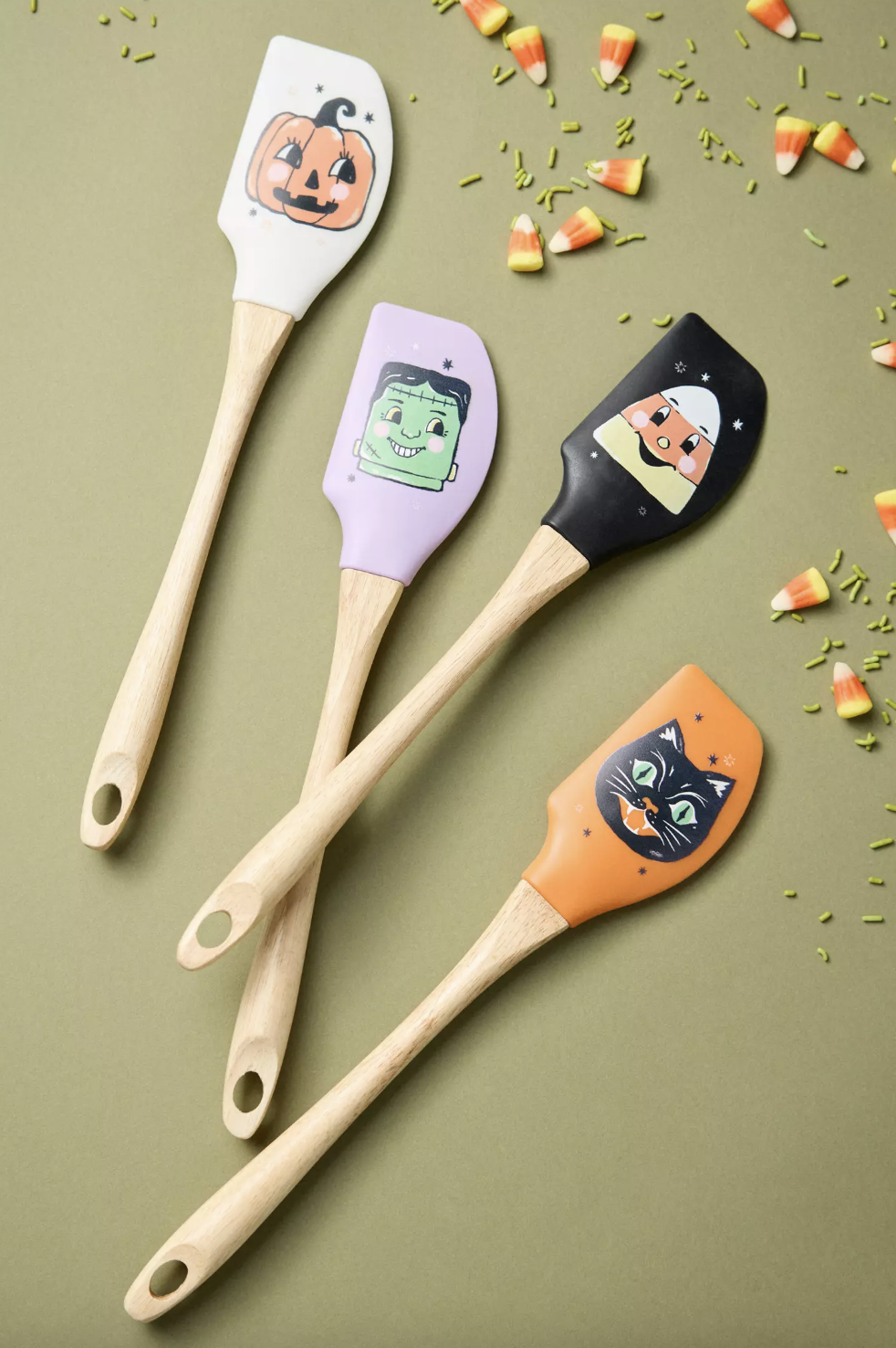 Four spatulas with Halloweenthemed designs including a pumpkin Frankenstein candy corn and a black cat