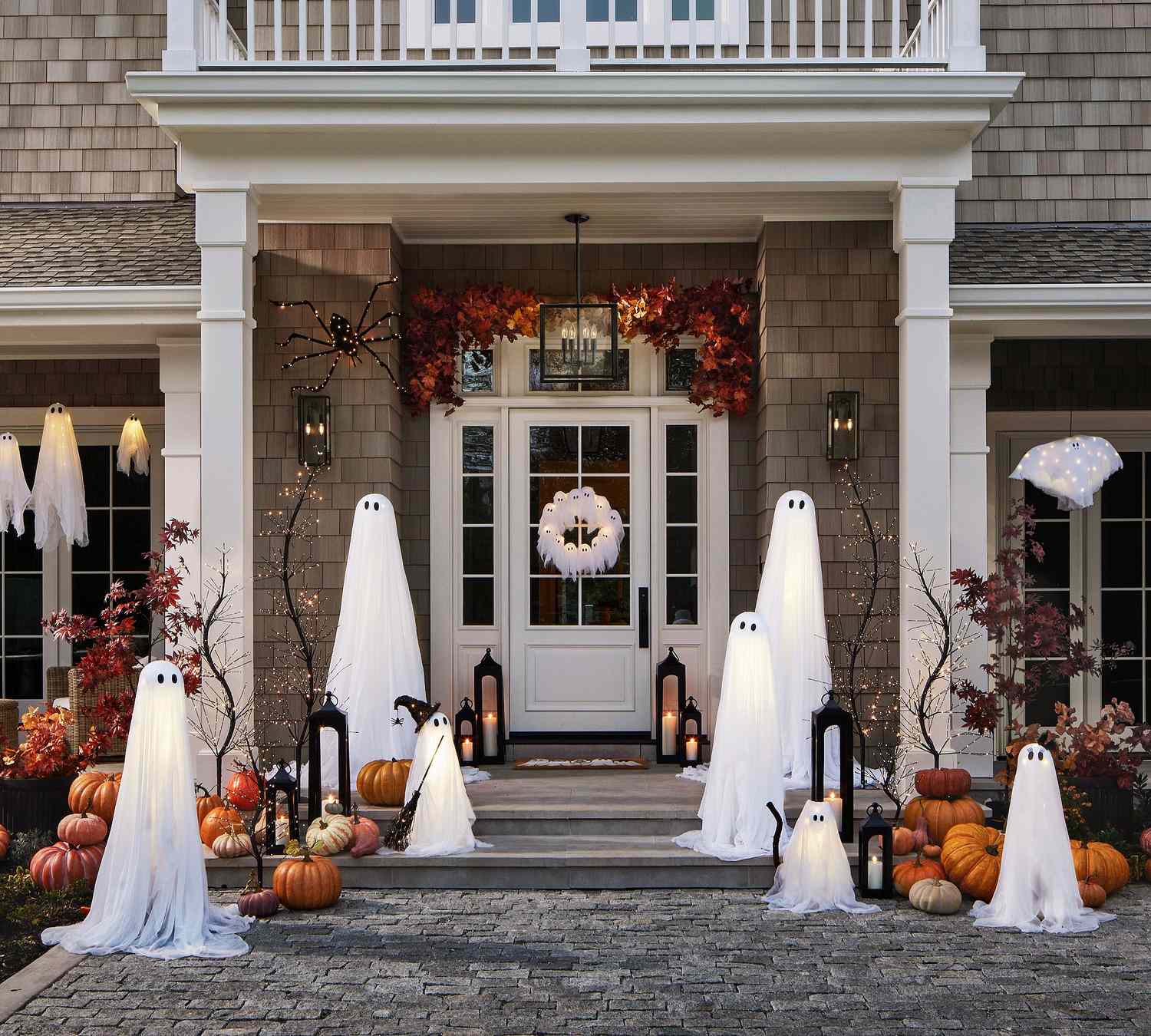 A house decorated for Halloween with ghost figures pumpkins and lights on the front porch