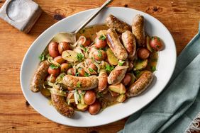 A plate of beerbraised sausages served with steamed redskinned potatoes and garnished with fresh herbs