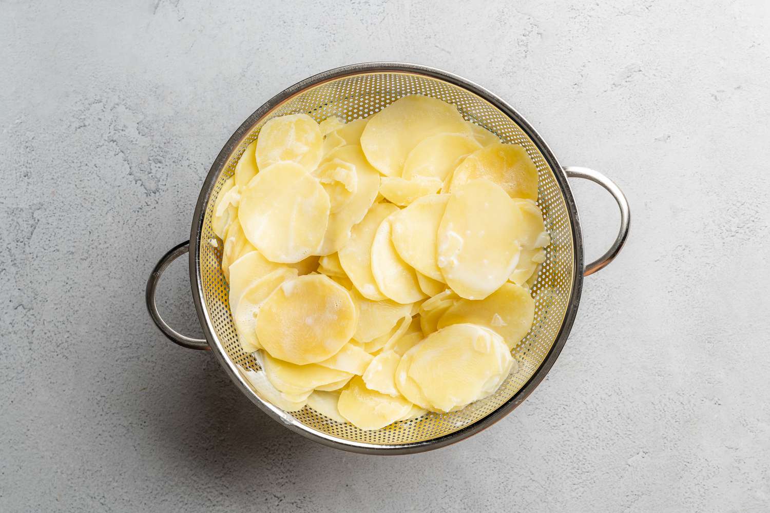 cooked sliced potatoes in colander 