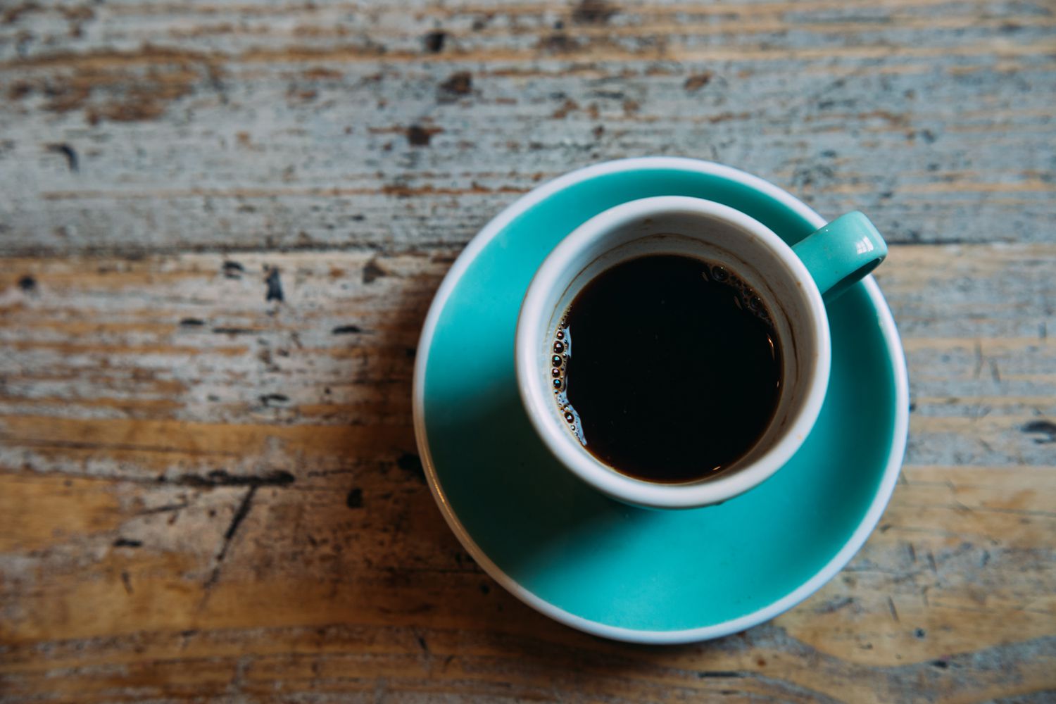 black coffee in turquoise cup on wooden surface