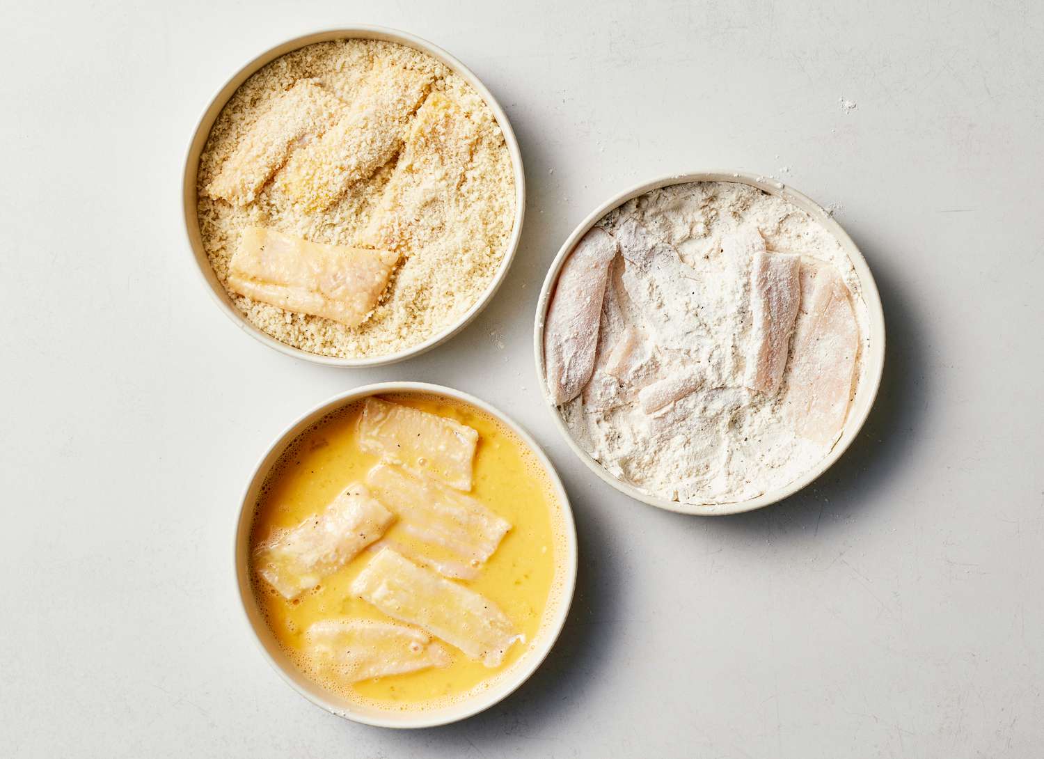 panko, flour, and eggs with fish dipped in three shallow dishes 