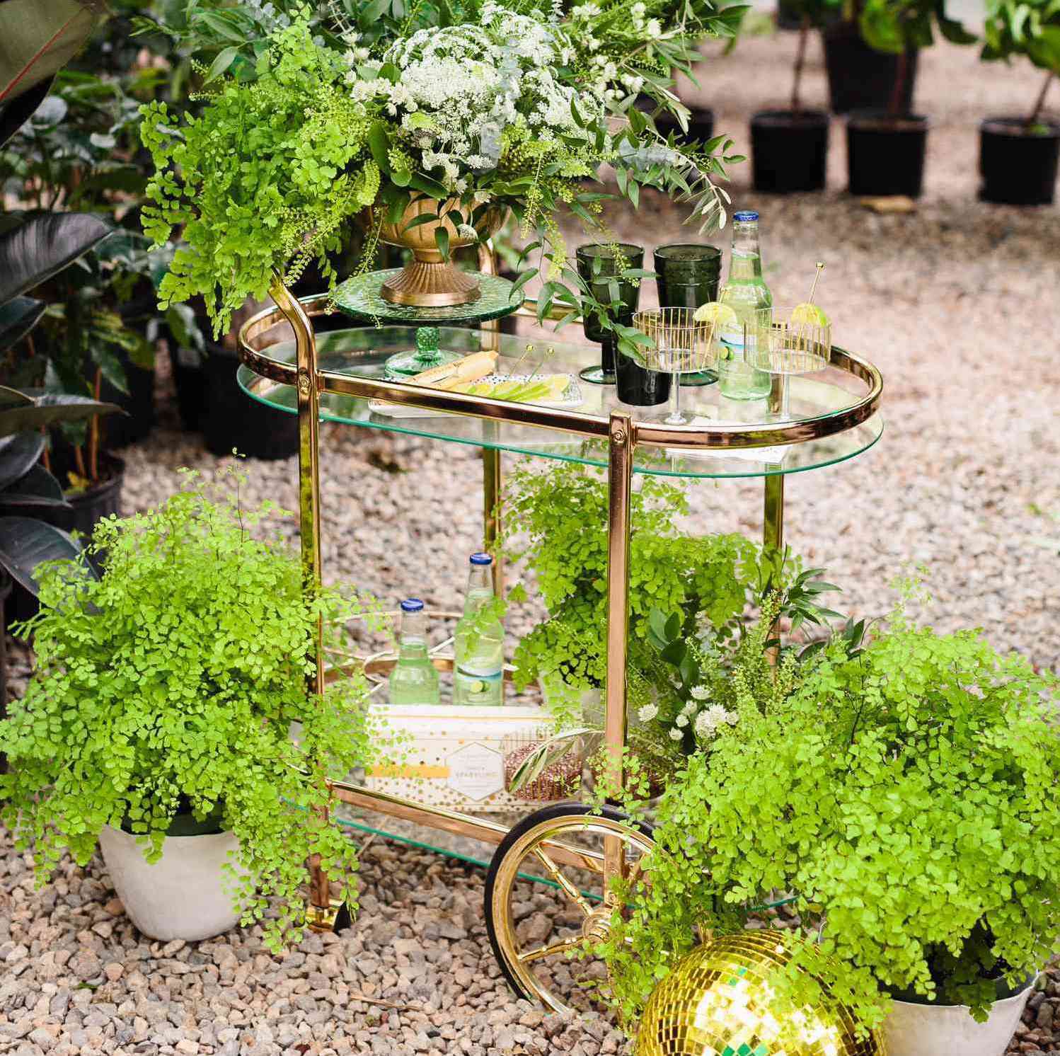 A cart outdoors with drinks and plants