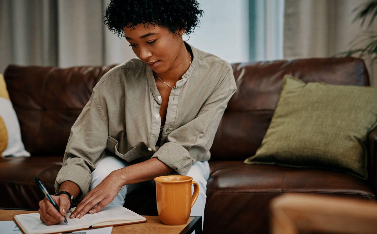 woman writing in journal sitting on sofa