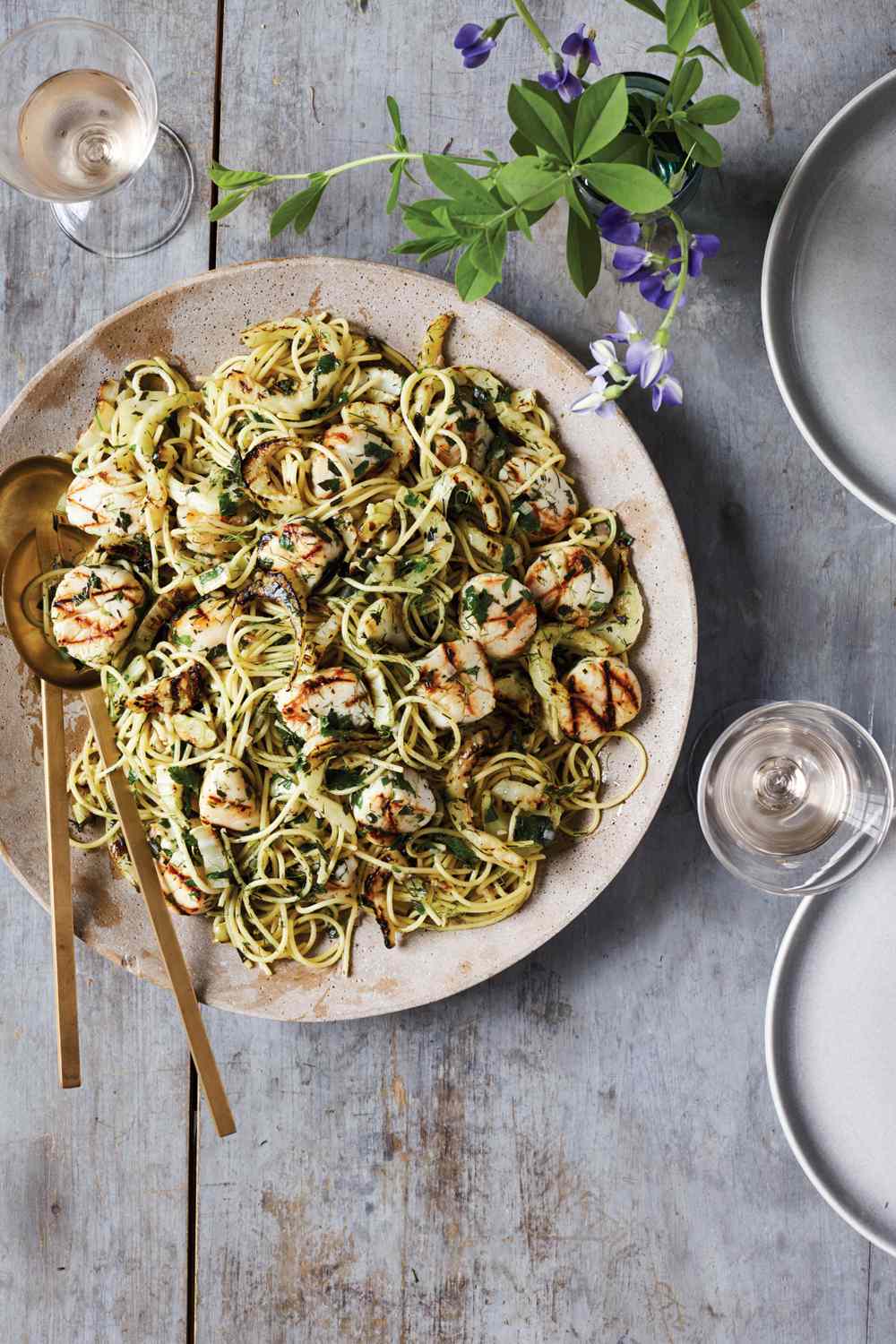 sea scallops over herb shallot pasta on a wooden tabletop