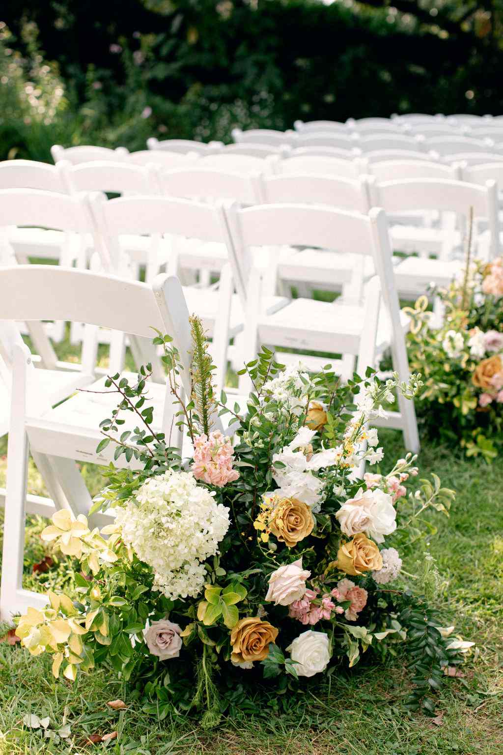 rows of white chairs wedding ceremony and floral aisle decor