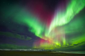 Aurora lights over a landscape with mountains and a dark sky