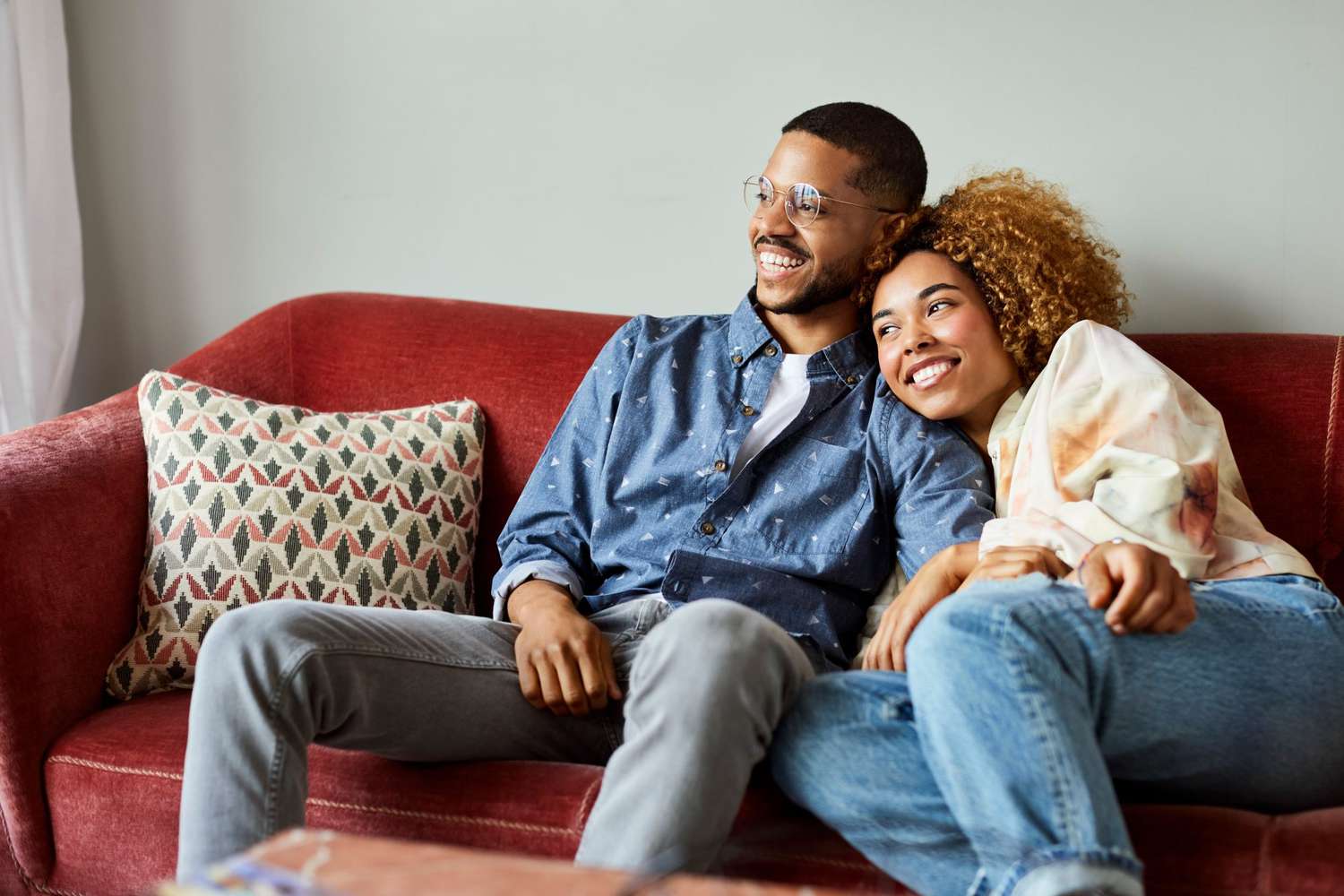 Couple watching movies together on red sofa