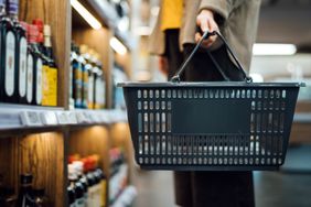 A person holding a shopping basket in a grocery aisle
