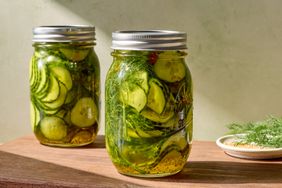 Jars of pickles with dill on a wooden surface