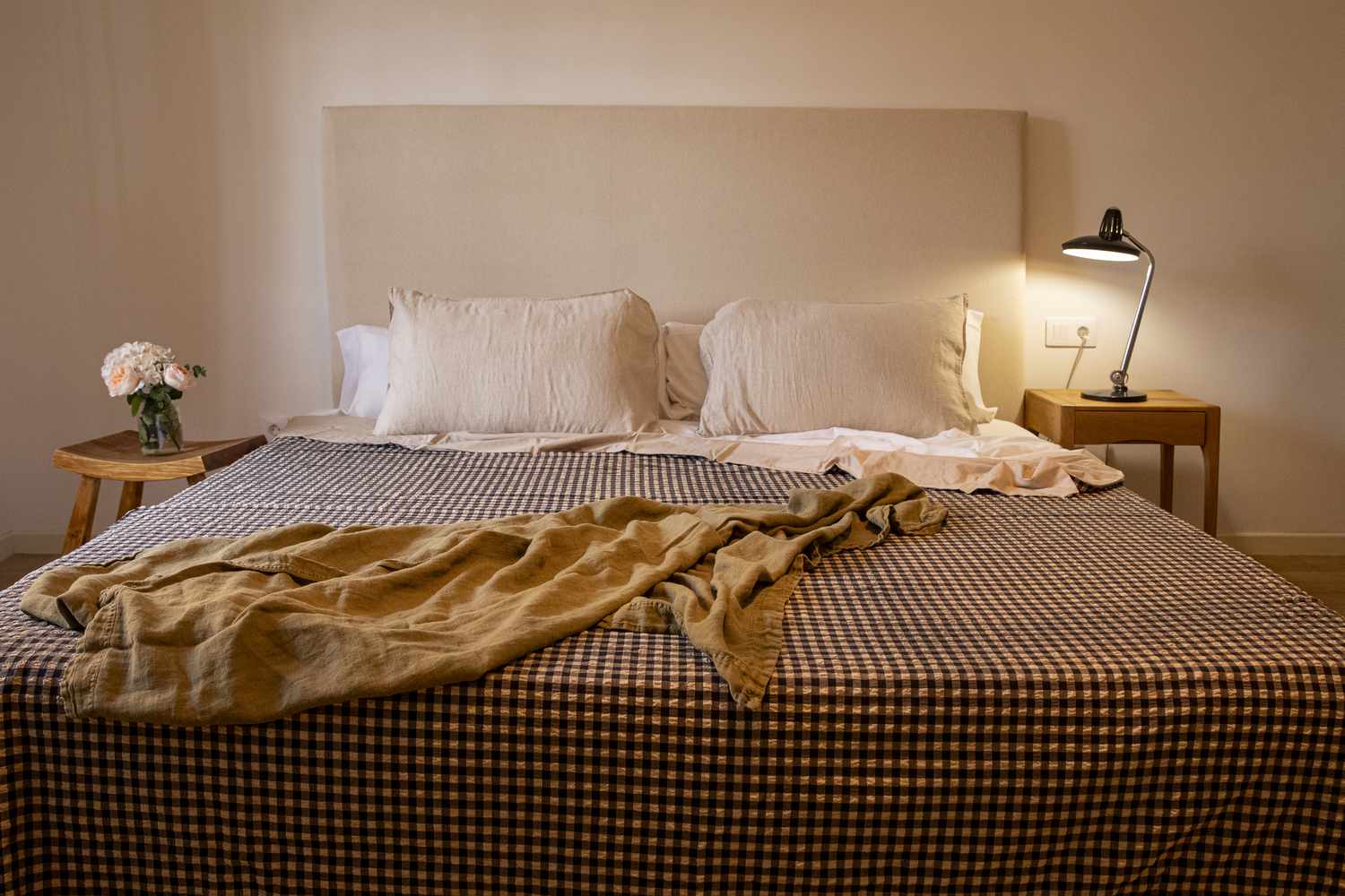 Cozy bed with bedside lamp lighting and floral bouquet. 