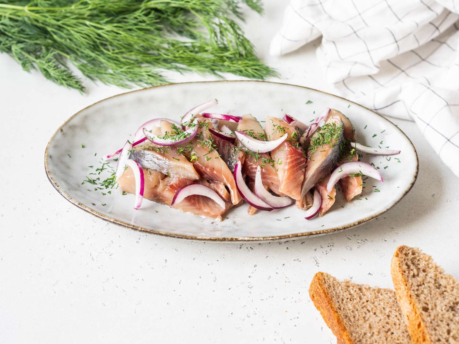 marinated herring slices with dill and red onion on plate