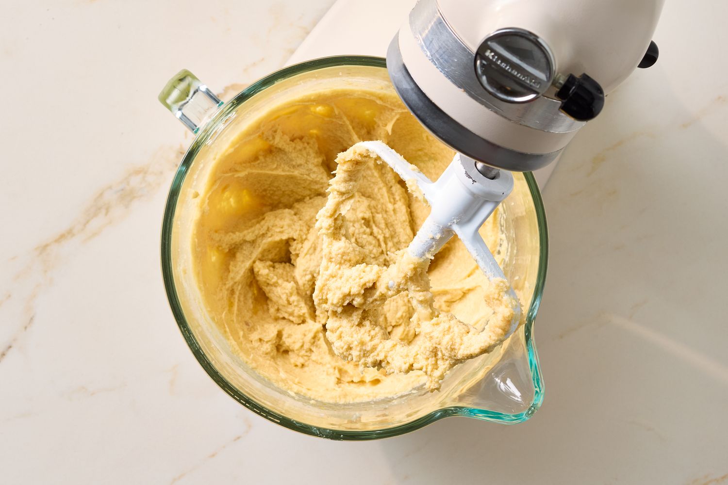 A mixer combining dough in a glass bowl on a surface